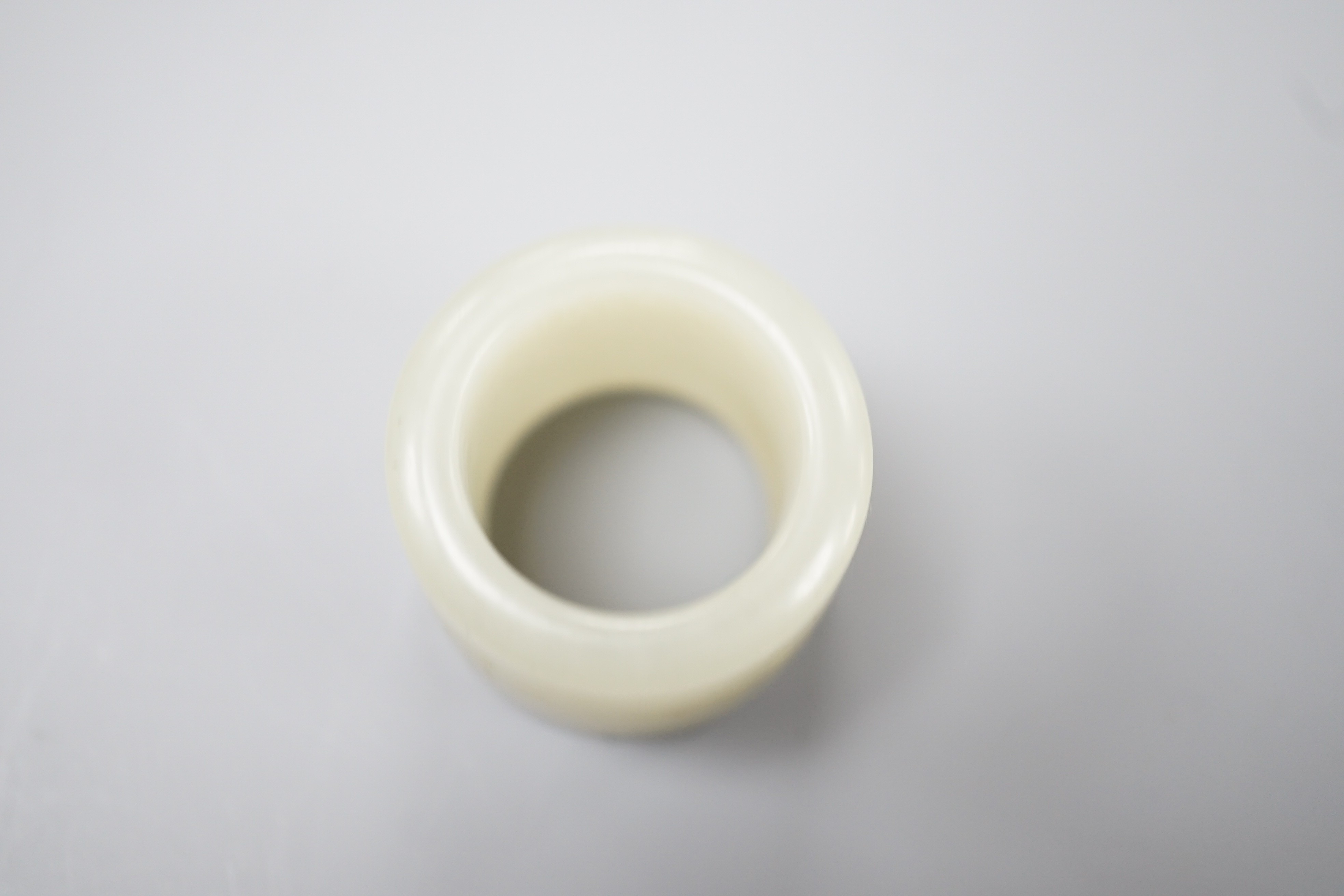 A 19th century Chinese pale celadon jade archer’s thumb ring, inscribed, 3 cm diameter